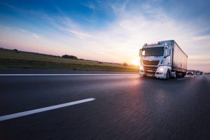 Loaded European truck on motorway in beautiful sunset light. On the road transportation and cargo.